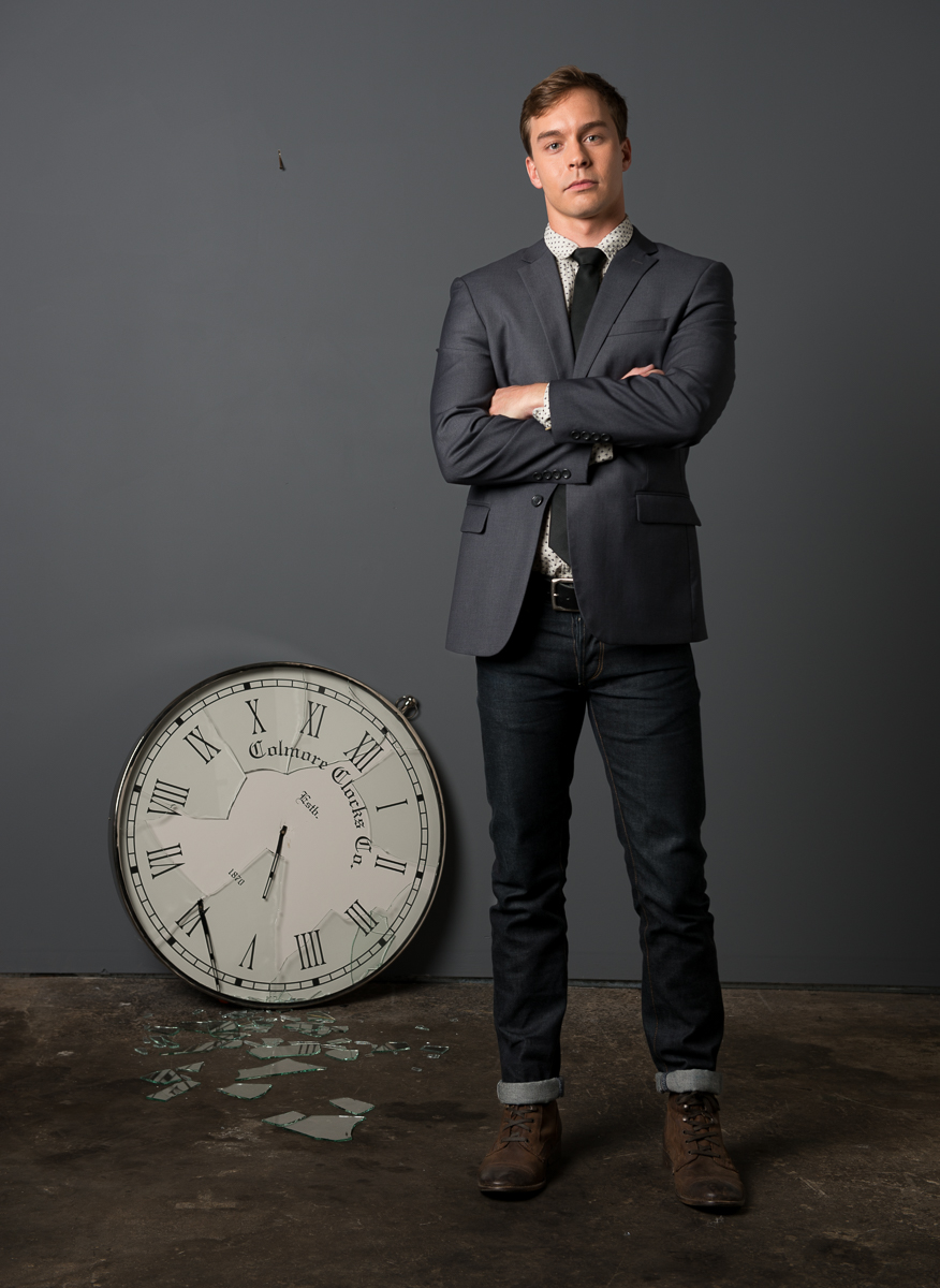 Portrait of man standing by broken clock