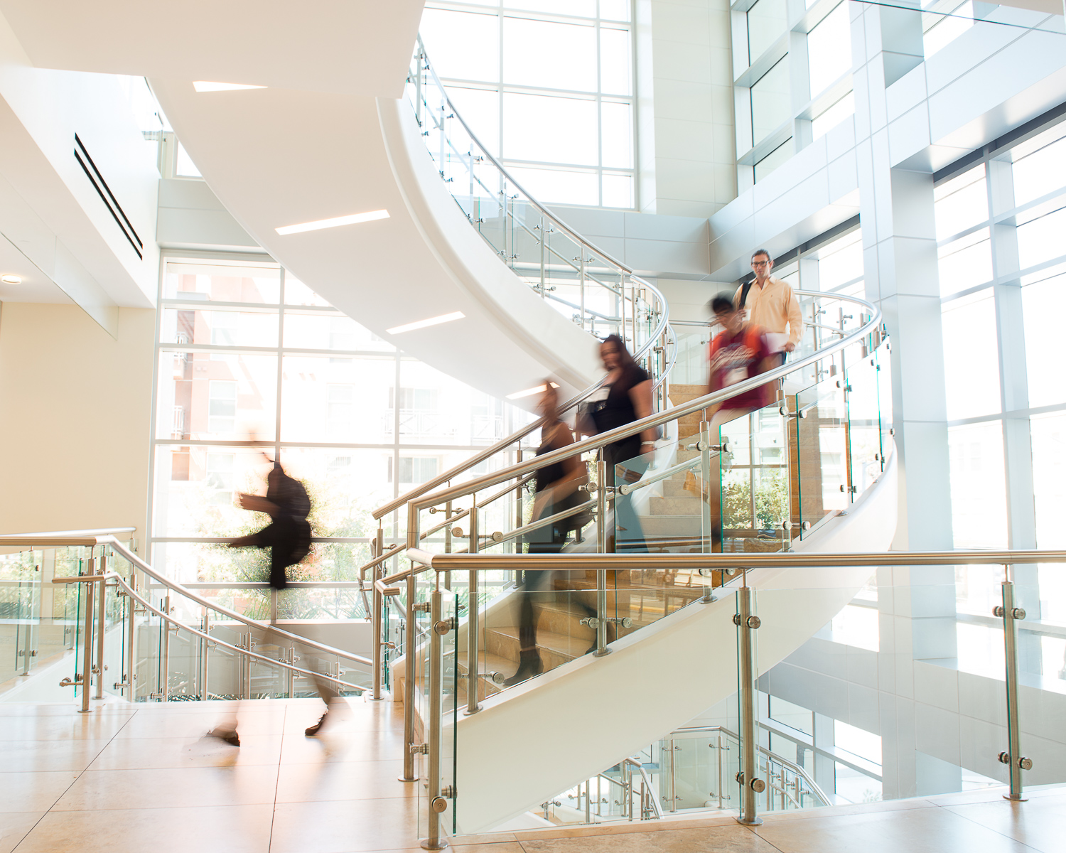 Students in motion descend glass staircase 