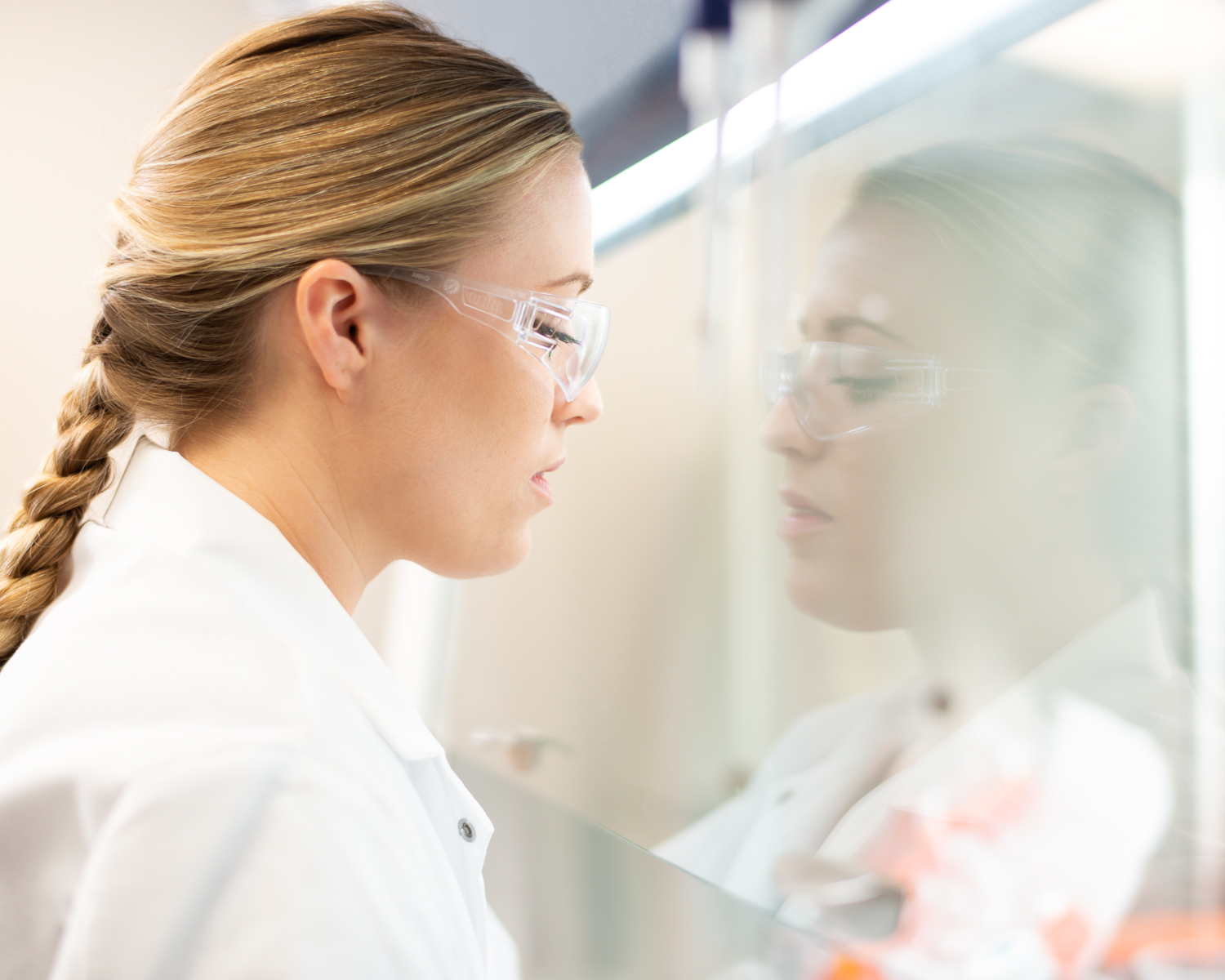 Female Scientist Reflects in Biotech Hood