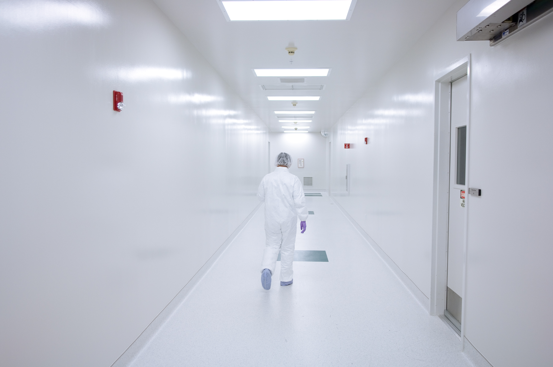 Fully gowned scientist walking hall in clean room