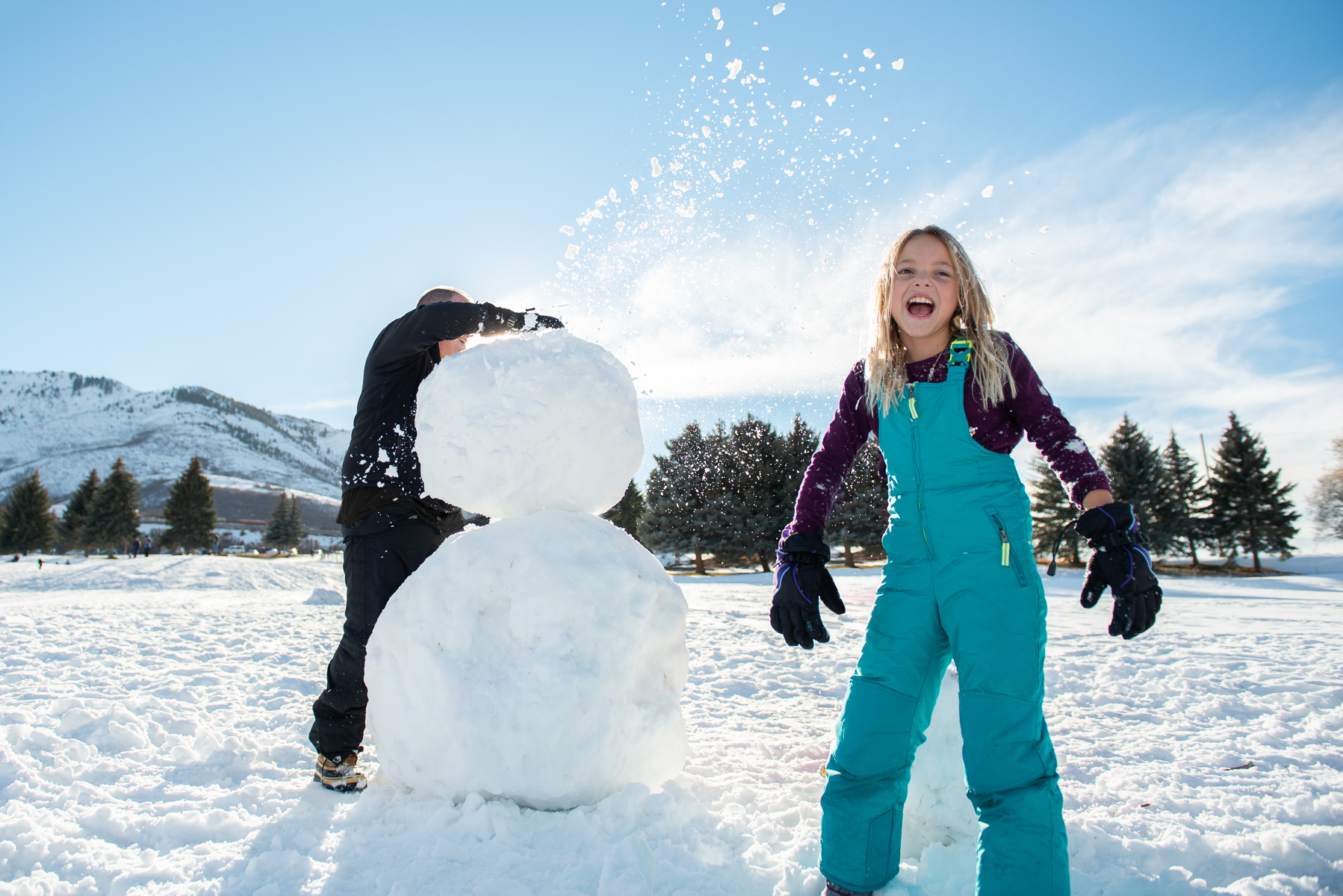 Snow flies over young girl from top of snowman